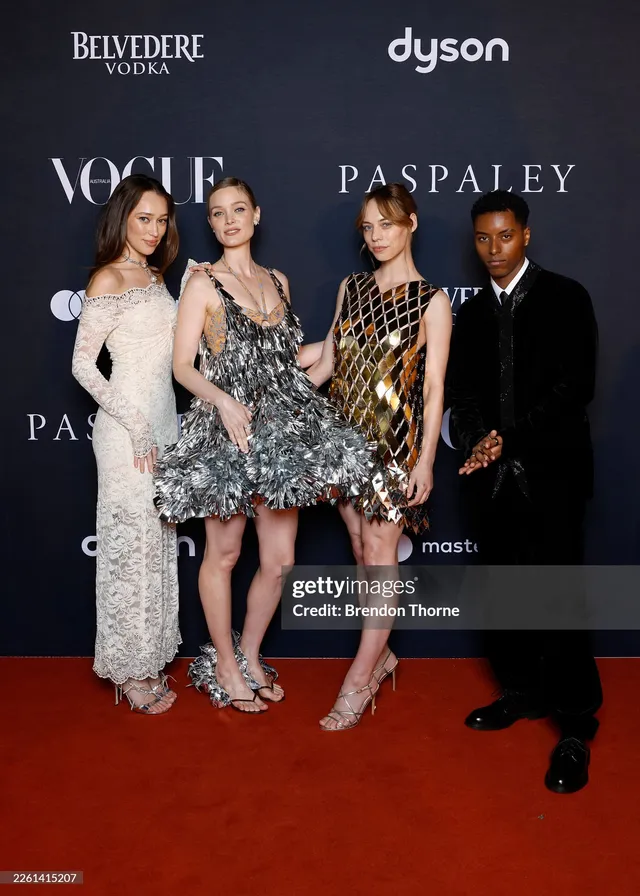 Alycia Debnam-Carey posing with companions at an event in a white dress.