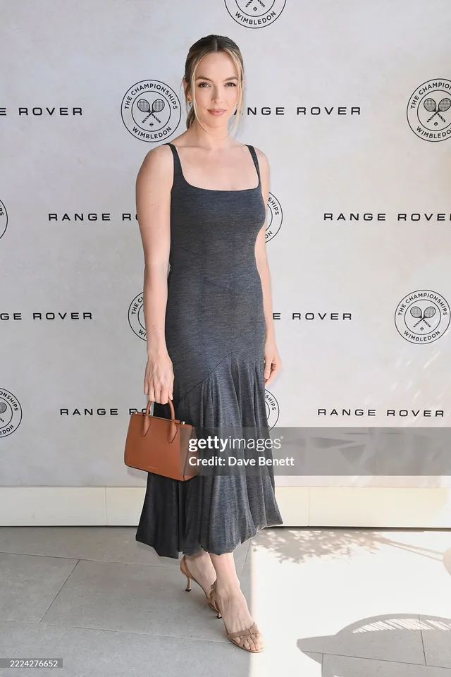 Jodie Comer posing at an event in a grey dress.