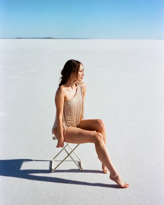 Alycia Debnam-Carey sitting on a chair in a bright open landscape.
