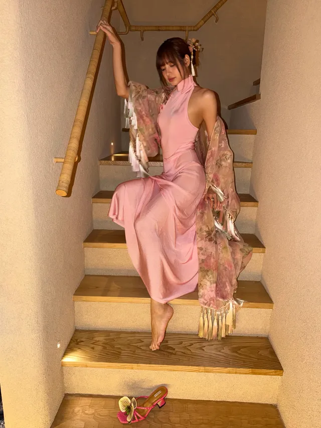 Lisa (Lalisa Manobal) sitting barefoot on indoor steps in a long pink dress.