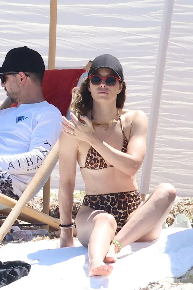 Jessica Biel seated on a boat in a patterned swimsuit.