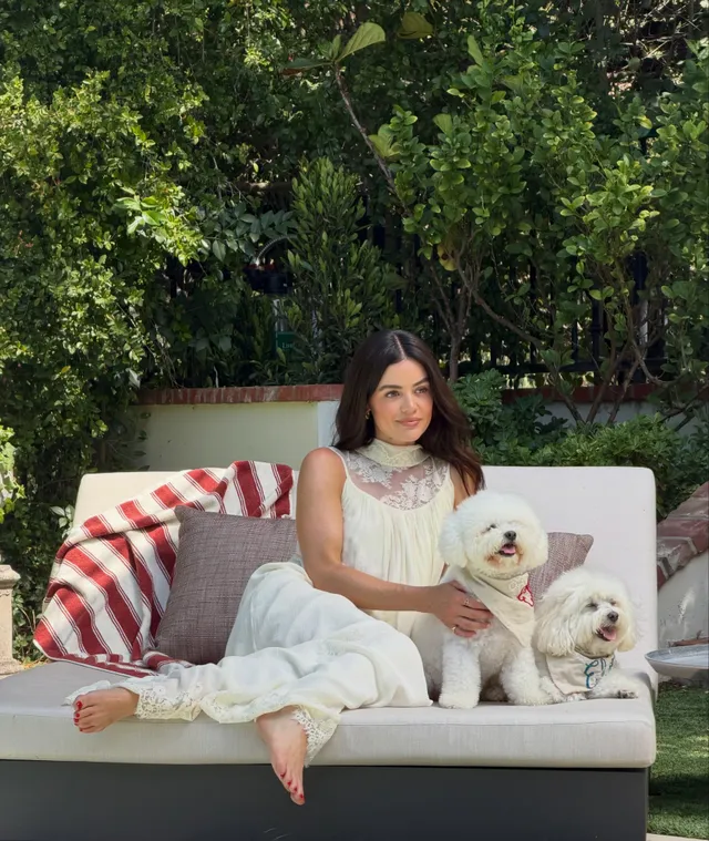 Lucy Hale relaxing on an outdoor sofa with two dogs.