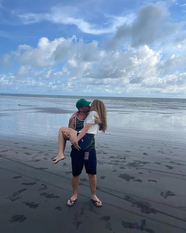 Teresa Palmer being carried by a companion at the beach.