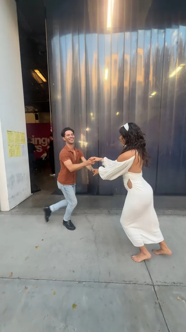 Xochitl Gomez dancing barefoot in a white dress beside a man.