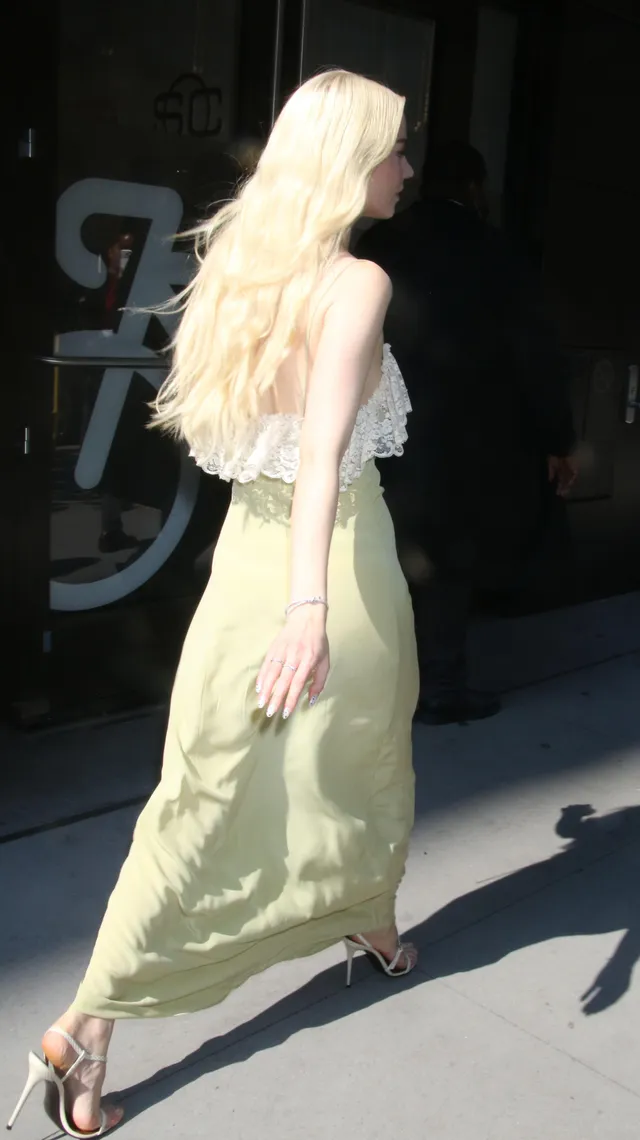 Anya Taylor-Joy walking outside in a pale outfit and metallic heels.