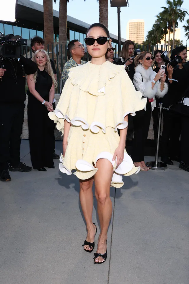 Chase Sui Wonders wearing a pale cape dress and black heels outdoors.