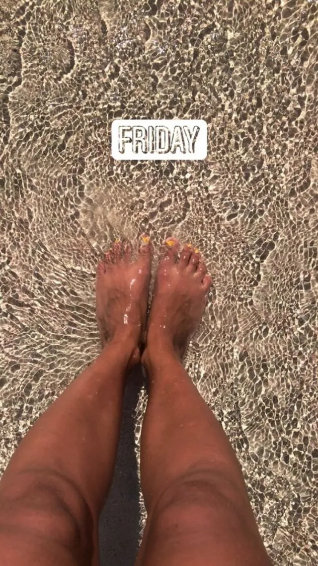 Ella Purnell standing in shallow water at a beach.