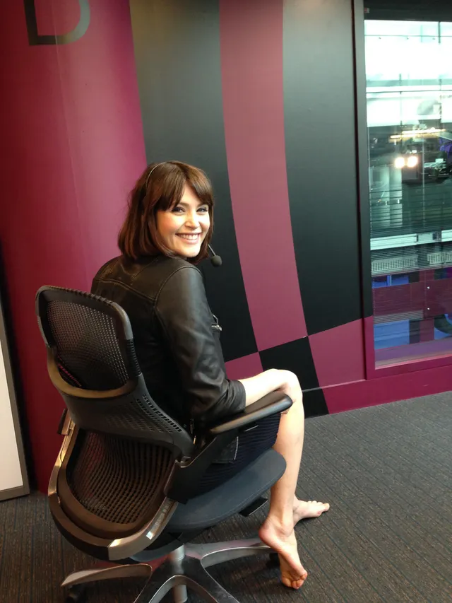 Gemma Arterton turning in an office chair with bare feet.