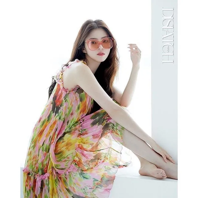 Han So-hee sitting barefoot in a floral dress.