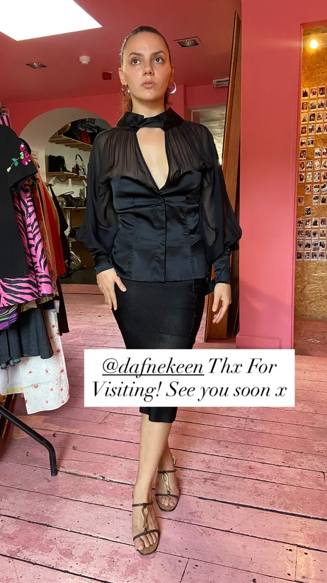 Dafne Keen wearing a black outfit and gold heeled sandals indoors.