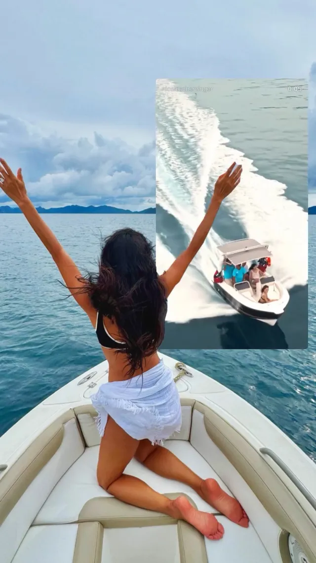 Nicole Scherzinger kneeling barefoot on a boat with her arms raised.