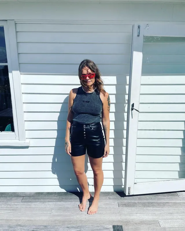 Tove Lo standing barefoot outdoors in a black top and shorts.