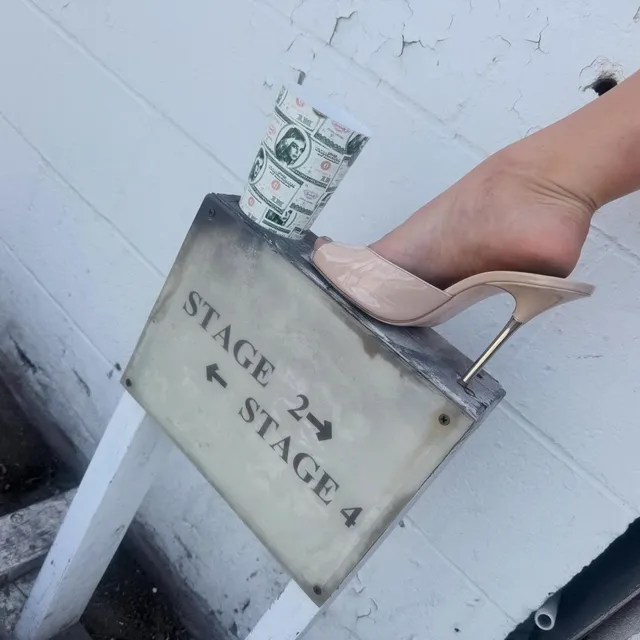 Addison Rae resting a beige heel on a backstage chair.