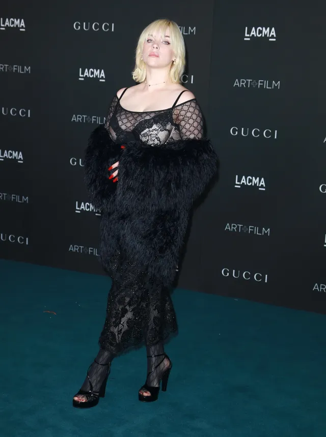 Billie Eilish a black lace outfit and heels at an event.