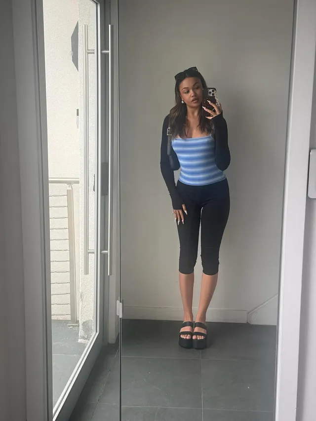 Madison Bailey taking a mirror selfie in cropped trousers and black platform heels.