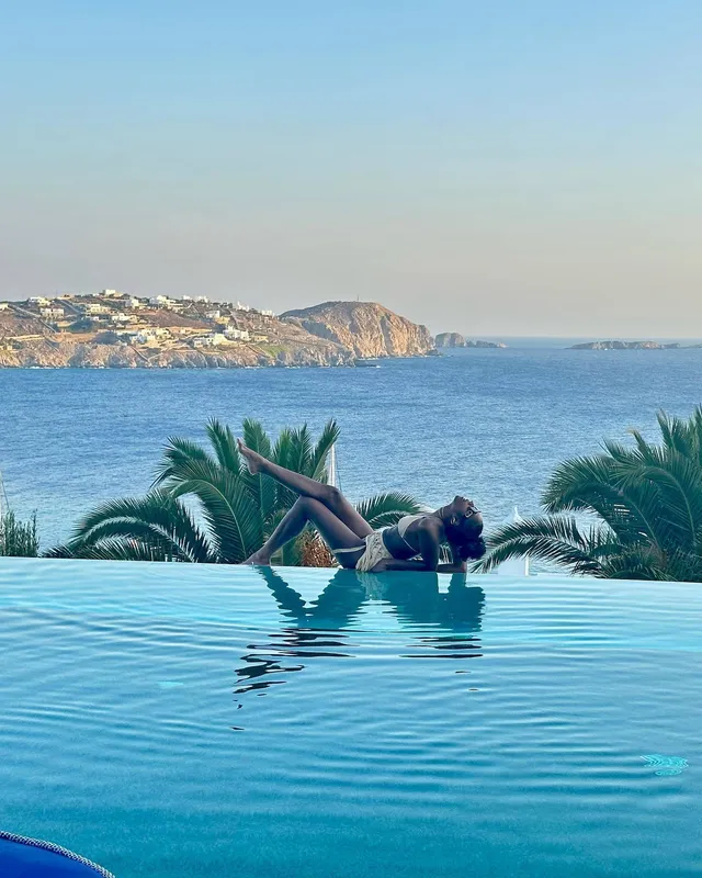 Carlacia Grant reclining barefoot beside an infinity pool.