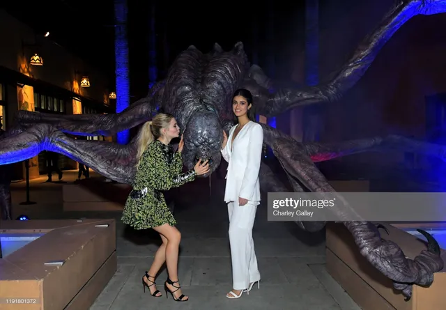 Anya Chalotra posing beside another woman in a white suit and heels.