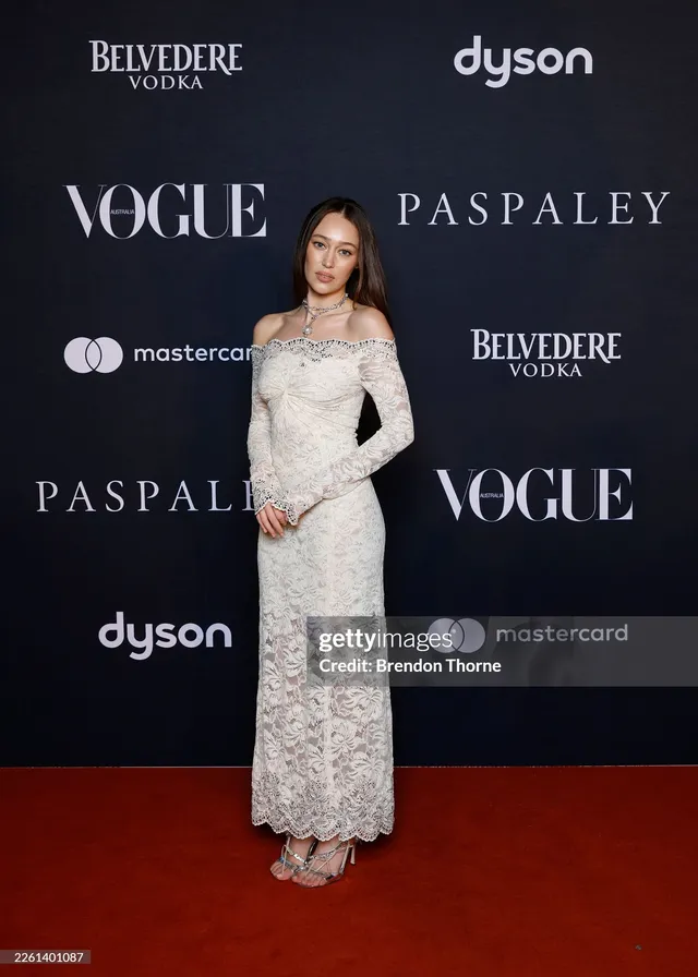 Alycia Debnam-Carey posing on a carpet in a white dress.