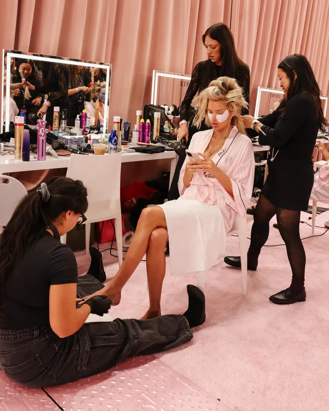Elsa Hosk sitting barefoot while a backstage team prepares her outfit.