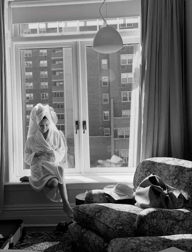 Phoebe Dynevor seated beside a window in a monochrome portrait.