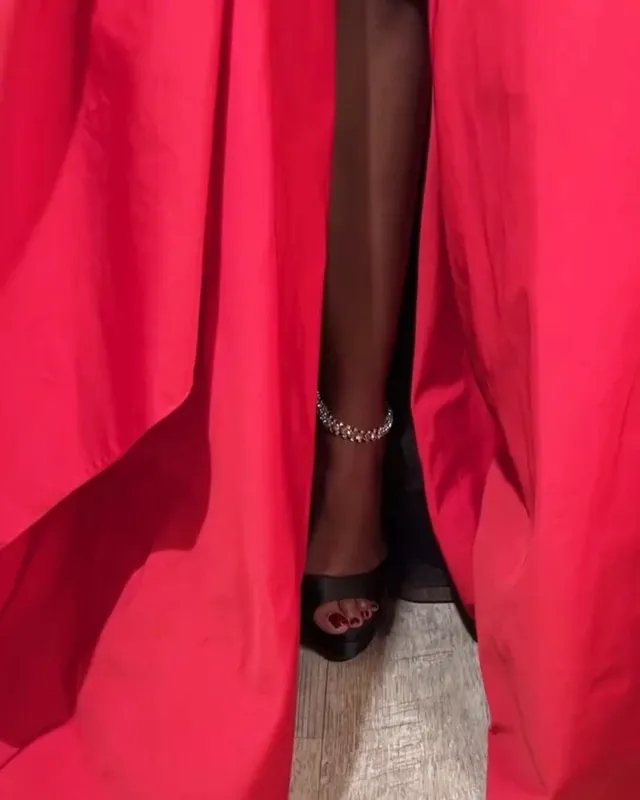 Carlacia Grant shown in a close-up wearing a black heel beneath a red gown.