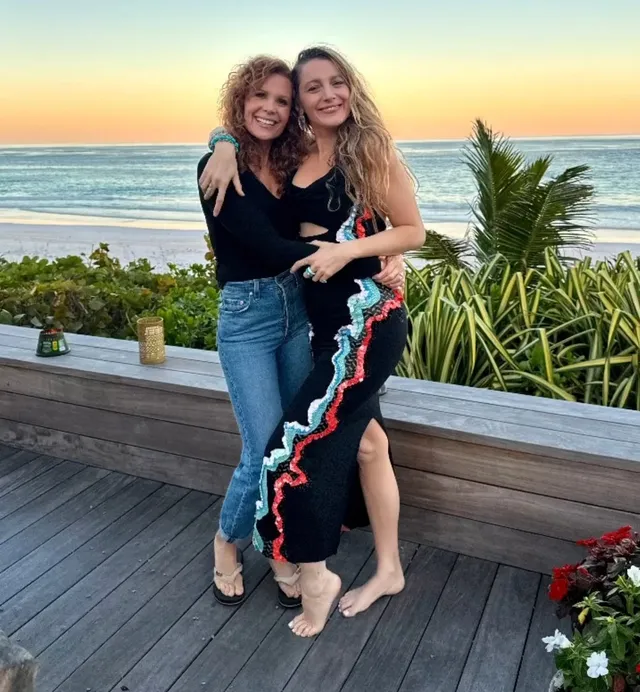 Blake Lively standing barefoot with a friend on a terrace.