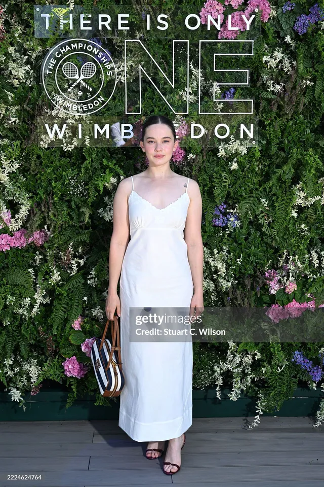 Cailee Spaeny posing in a pale dress and black heels at Wimbledon.
