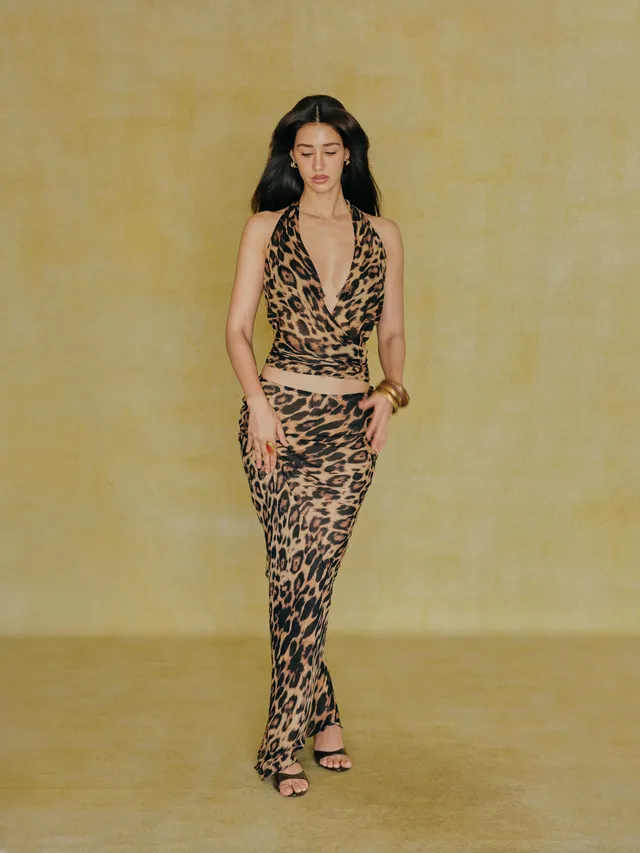 Disha Patani standing in heeled sandals and a leopard-print dress during a studio shoot.