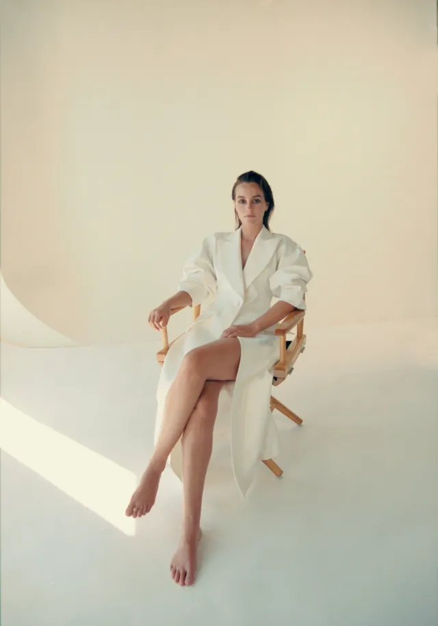 Leighton Meester sitting on a chair in a white outfit.