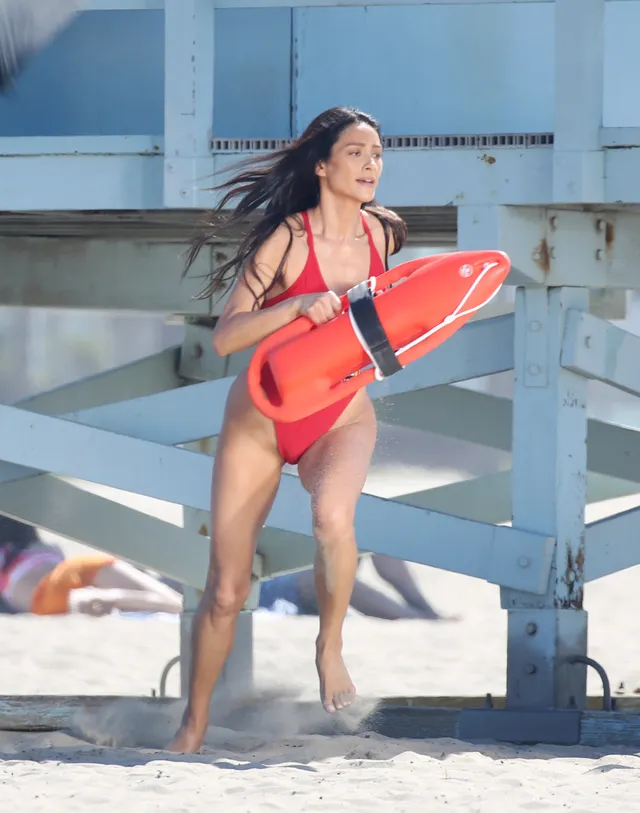 Shay Mitchell standing on a beach with rescue equipment.