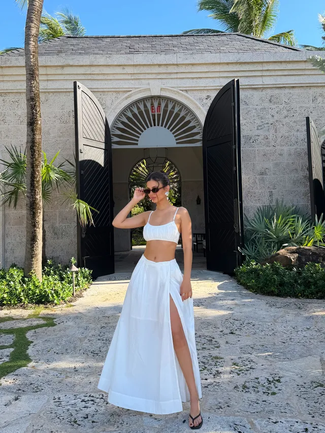 Victoria Justice standing outdoors in a white outfit and flat sandals.