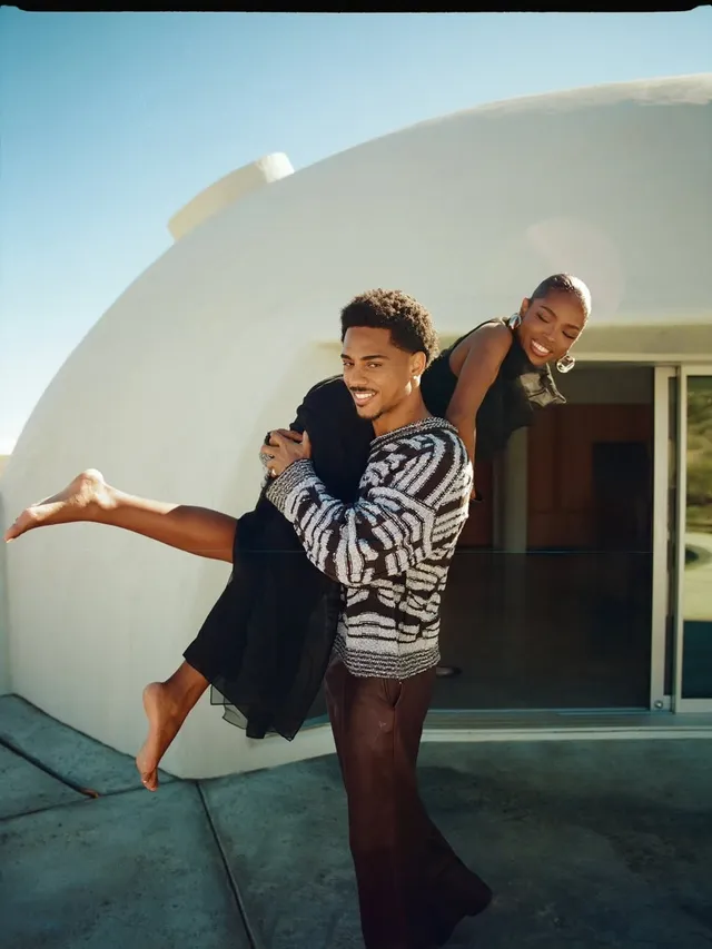 Ryan Destiny being carried by a man outdoors with a bare foot extended.