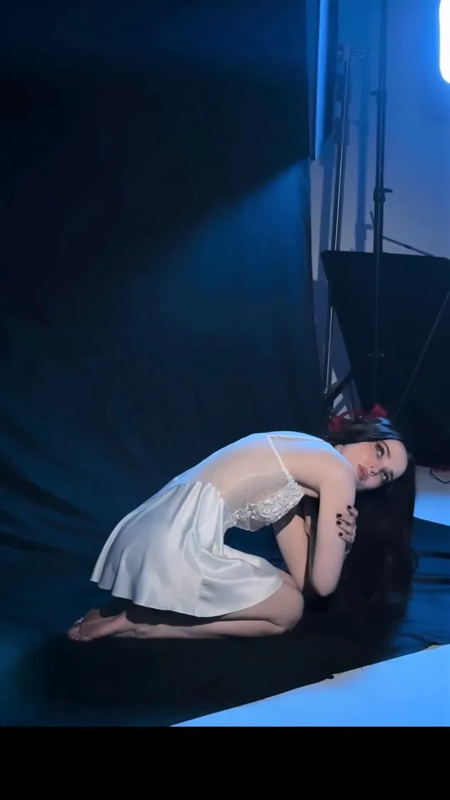 Dove Cameron kneeling barefoot during a stage performance.