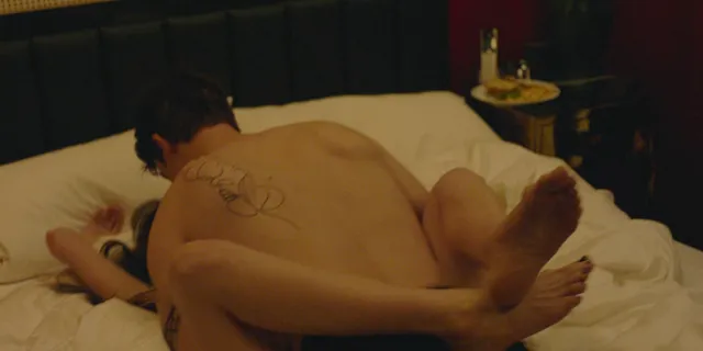 Anne Hathaway reclining on a bed with a bare foot raised.