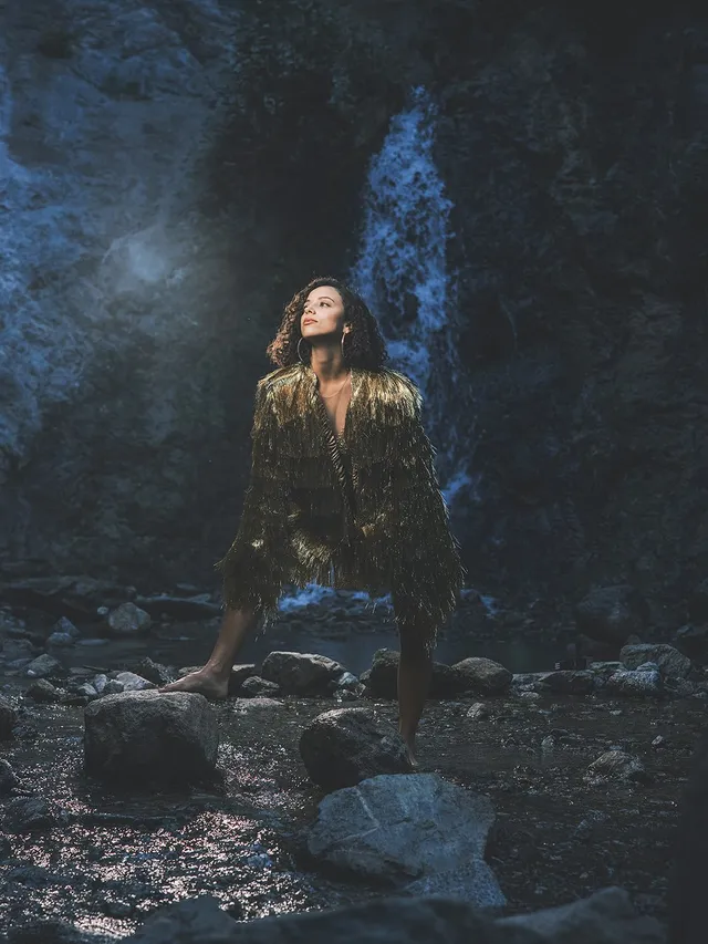 Kiana Madeira posing barefoot on a rock in a flowing patterned outfit.