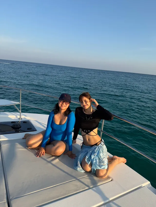 Lisa (Lalisa Manobal) sitting barefoot beside a companion on a boat deck.