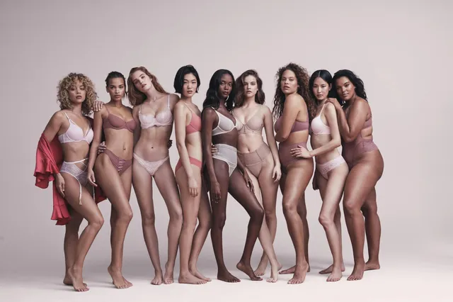 Barbara Palvin posing barefoot with a group in a studio.