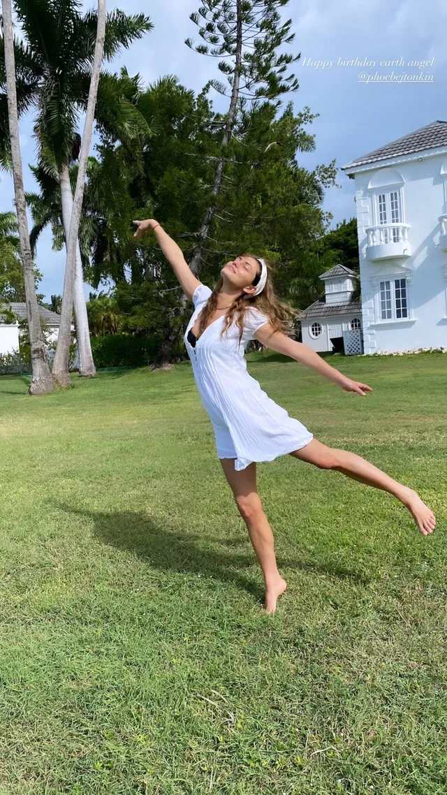 Phoebe Tonkin posing on grass in a pale dress.