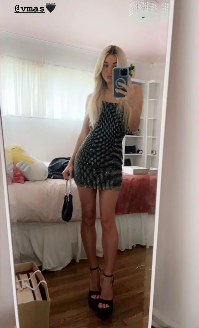 Olivia Dunne taking a mirror photo wearing a black dress and heels.