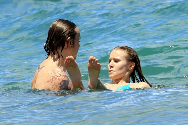 Kristen Bell swimming beside another person in blue water.