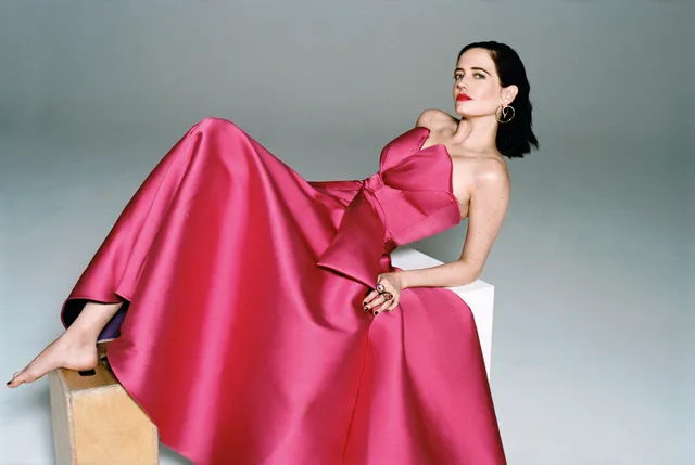 Eva Green reclining in a pink gown against a grey backdrop.