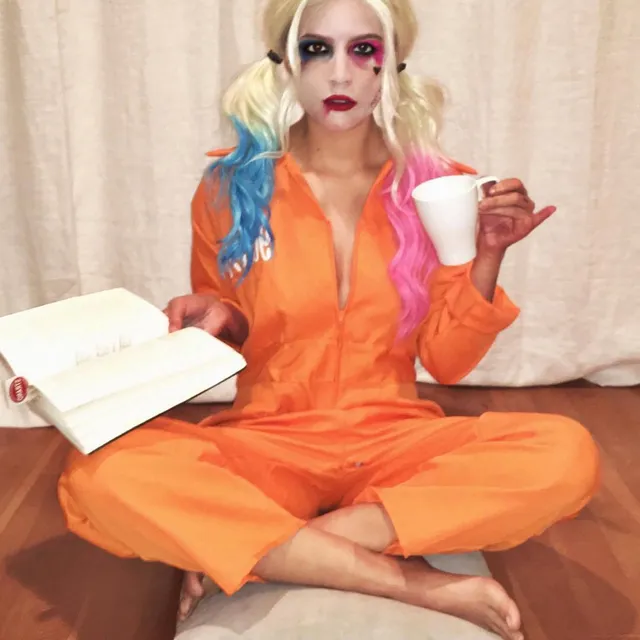 Halsey sitting cross legged barefoot in an orange outfit.