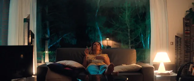 Adèle Exarchopoulos reclining on a sofa in a screen scene.