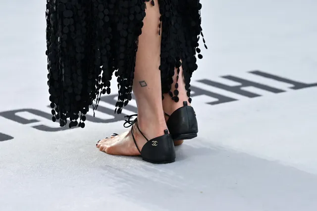 Margaret Qualley a rear detail of black heels beneath a fringed dress.