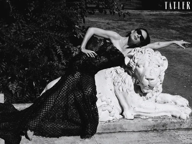Hayley Atwell reclining on a bench in a monochrome fashion portrait.