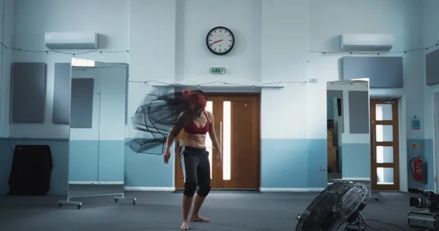 Naomi Scott standing barefoot in a bright rehearsal room.