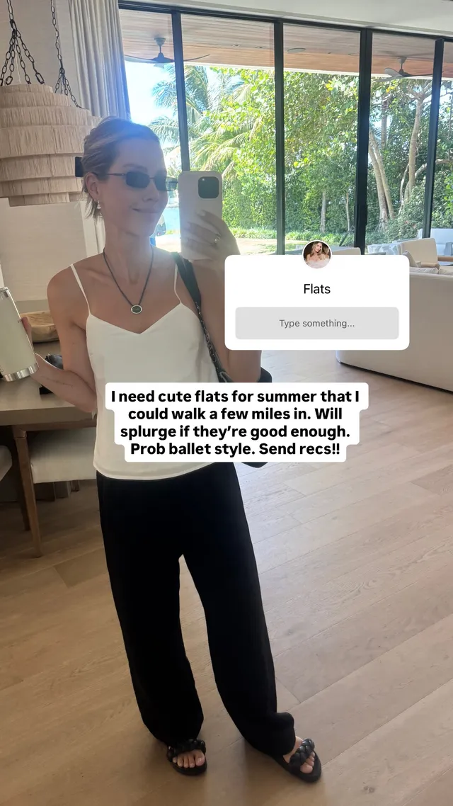 Claire Holt taking a mirror portrait in dark trousers and flat shoes.