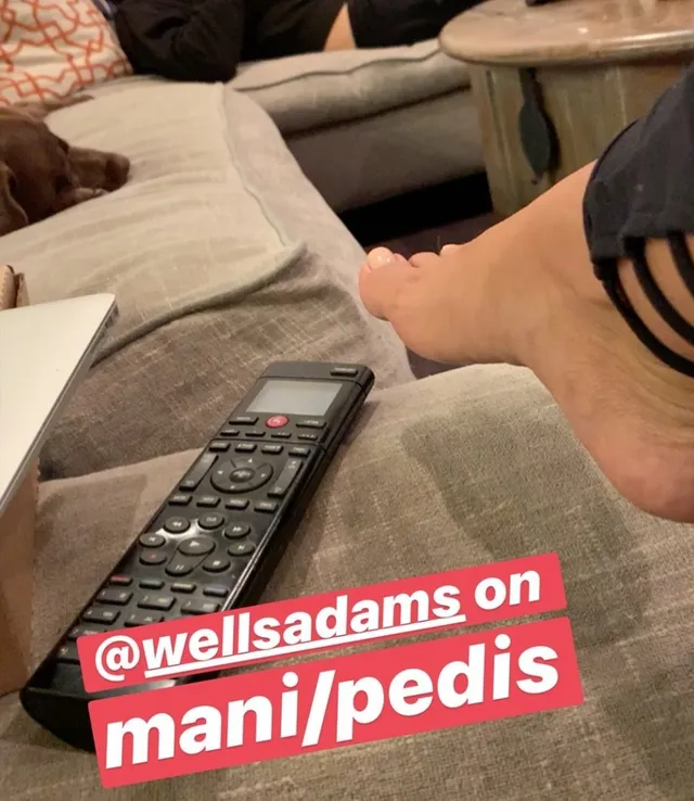 Sarah Hyland a close-up of a bare foot beside a television remote.