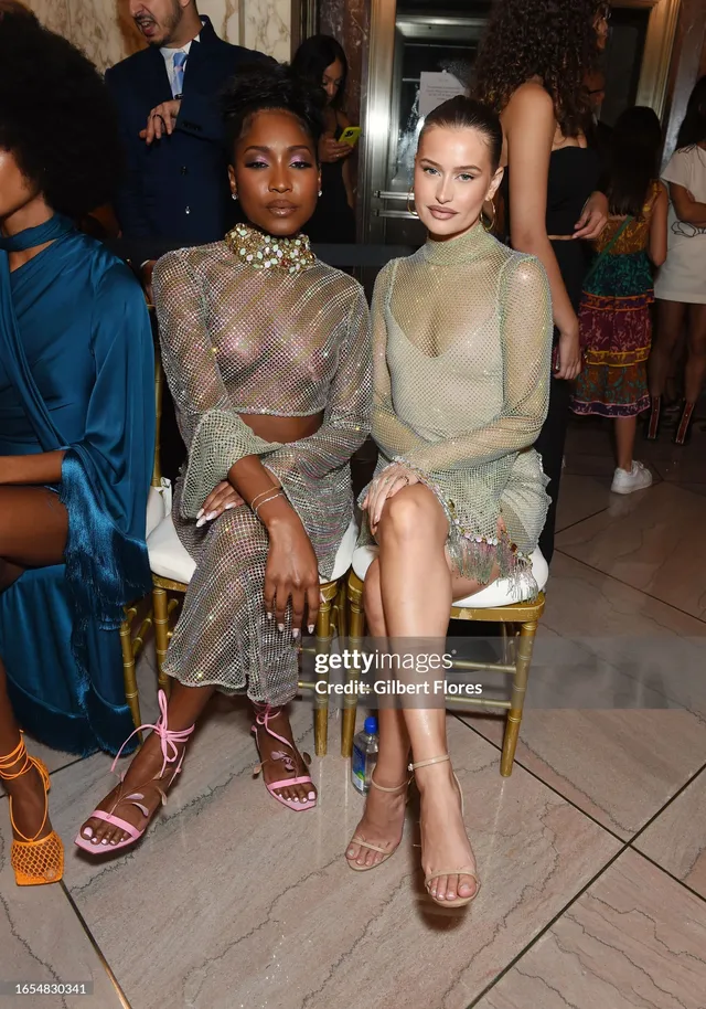 Carlacia Grant sitting beside a guest in a silver outfit and pink heels.
