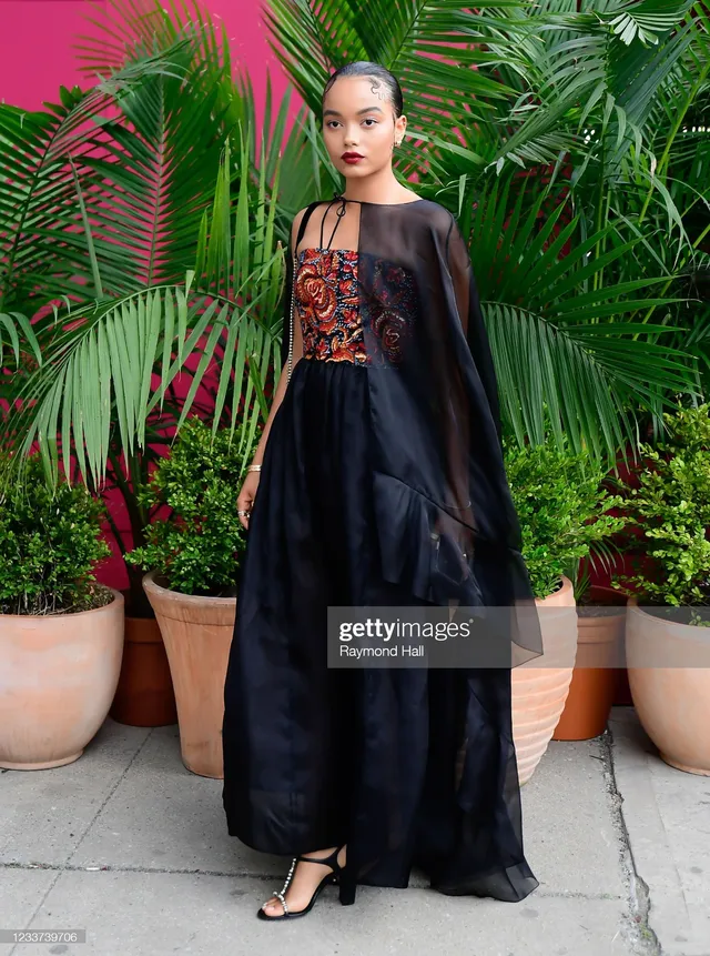 Whitney Peak posing outdoors in an embellished top, long dark skirt and heels.